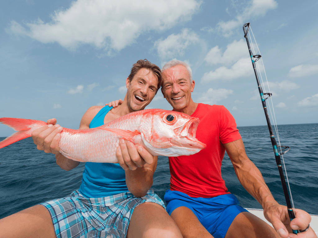 2 men holding a fish they caught while deep sea fishing