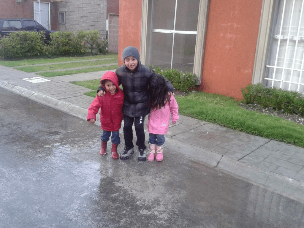 3 children playiing in the rain in Merida Mexico