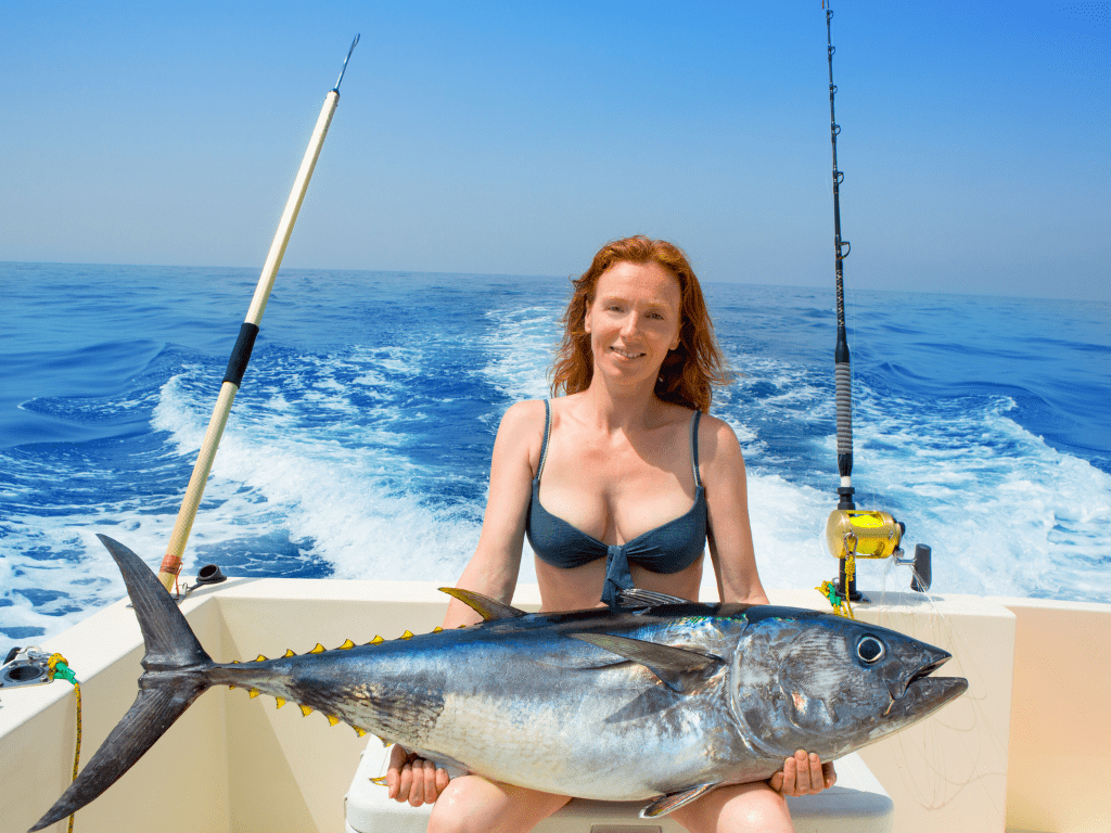 woman holding a tuna while on a fishing charter boat